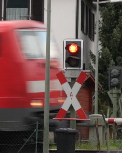 Ampel am Bahnübergang mit vorbeifahrendem Zug 