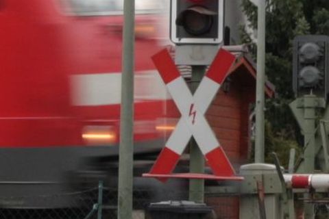 Ampel am Bahnübergang mit vorbeifahrendem Zug
