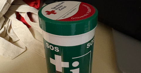 Eine Notfalldose in grün mit weißem Aufdruck SOS, Kreuz, ...