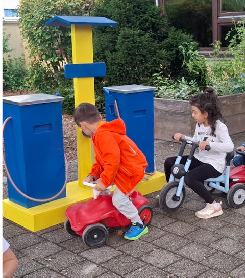 Kinder sitzen auf Fahrzeugen vor der Tankstelle