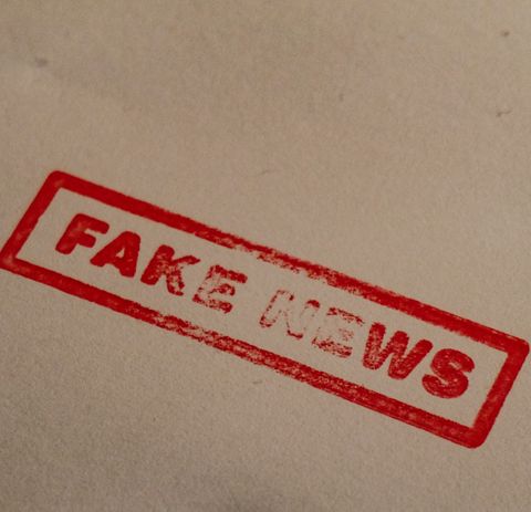 Ein Stempel mit dem Aufdruck Fake News auf einem Papier
