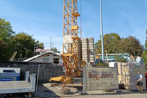 Baustelle am Kindergarrten Stockwiesenweg: Im Hintergrund das Gebäude mit Gerüst, im Vordergrund Bauzaun und Kran